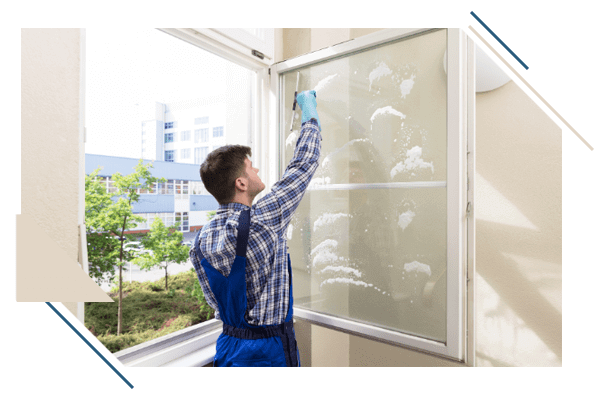 Glasreinigung - Mann steht am Fenster und putzt es